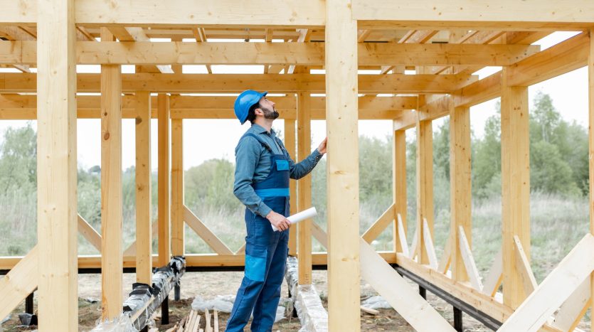 Builder on the wooden house structure on the construction site