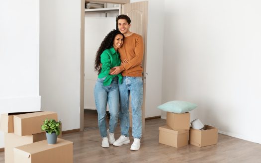 Happy millennial couple posing on moving day in new flat