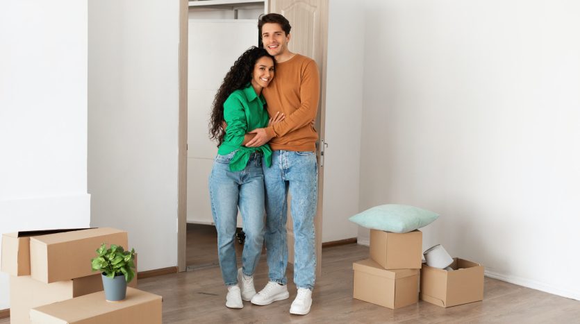 Happy millennial couple posing on moving day in new flat