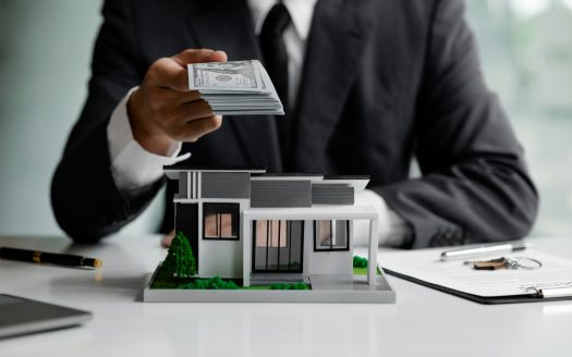 A person holding a certain amount of money with the housing model of the project.