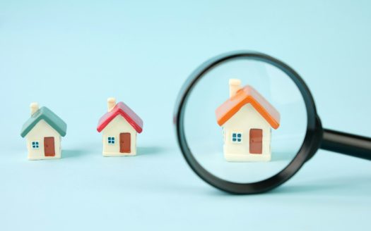 Small houses under a magnifying glass. Real estate search concept, purchase and sale of housing